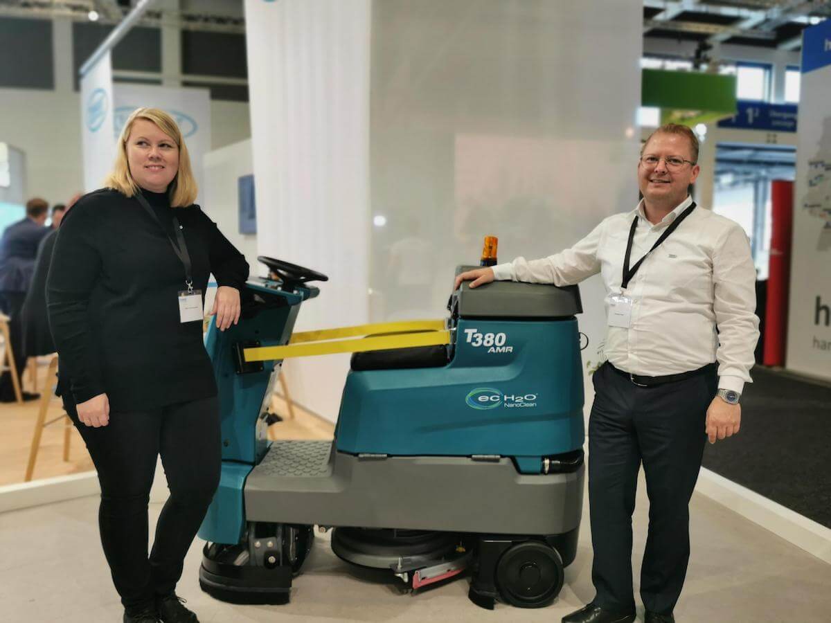 Verkaufsleiter Gesundheitswesen Dirk Vosshall von Tennant (rechts) und eine Mitarbeiter zeigen die neue Scheuersaugmaschine auf der CMS Berlin